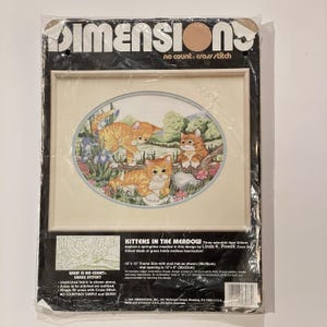 May include: A Dimensions no count cross stitch kit titled Kittens in the Meadow featuring three orange tabby kittens in a grassy field. The packaging includes a 15 inch by 12 inch frame size with an oval mat opening of 12 inches by 9 inches.