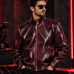 May include: A dark red and black snakeskin-patterned jacket with a high collar, gold-tone front zipper, and gold-tone buttons on the collar and cuffs. The jacket features a structured fit with long sleeves and a textured, glossy finish.