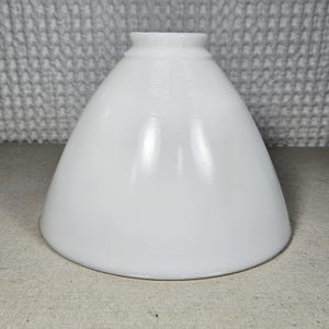 May include: A conical white glass lamp shade featuring a smooth, glossy finish and a series of subtle, horizontal ribbed lines encircling the narrow top opening. The shade has a wide, flared base and a clean, minimalist structural design.