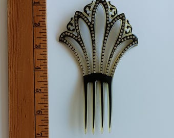 May include: A black hair comb with a fan-shaped top featuring clear rhinestones along the edges and cutouts. A wooden ruler is placed next to the comb, showing it measures approximately 6.5 inches in total length.
