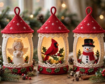 May include: Three crocheted lantern ornaments with red pointed roofs featuring white star embroidery. Each lantern houses a different figure: a white angel, a red cardinal bird on a branch, and a snowman wearing a black top hat.