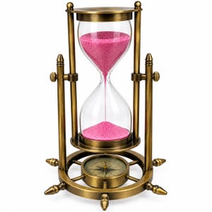 May include: An antique-style brass hourglass featuring a rotating frame with a ship's wheel base. The glass bulbs contain vibrant pink sand. The base includes an integrated compass with a circular dial, and the frame is secured by side knobs.