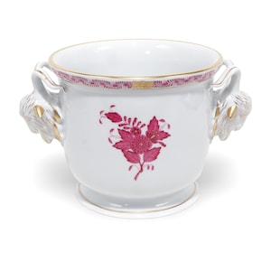 Op de afbeelding: Een witte porseleinen pot met een centraal magenta bloemmotief en een goudkleurige rand. De houder is voorzien van twee zijhandgrepen in de vorm van dierenkoppen met gouden accenten en een decoratieve magenta rand langs de bovenkant.