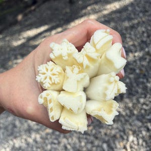 Può includere: Una collezione di piccoli timbri in schiuma color bianco sporco con varie forme a tema natalizio, tra cui un fiocco di neve, un angelo, un fiocco, un bastoncino di zucchero, un albero di Natale e un omino di pan di zenzero, raggruppati per il fai da te.
