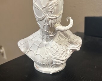 May include: A white 3D printed bust featuring a split design. One side depicts the classic webbed mask of Spider-Man, while the other side shows the textured, organic features of Venom, including a sharp-toothed mouth and a long, protruding tongue.