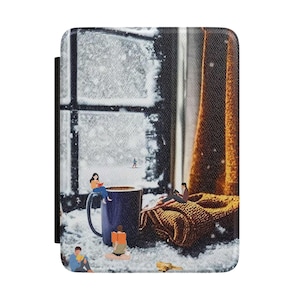 May include: A rectangular e-reader cover featuring a printed scene of a snowy window with a dark blue mug, a brown knitted blanket, and several miniature figures reading books. The design includes a person skiing in the distance and a small dog.