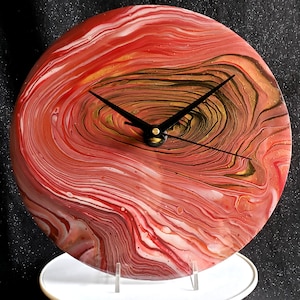 May include: Red, white, and gold abstract clock with black hands. The clock face has a swirling, marbled design.