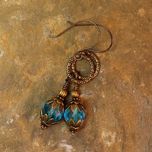 May include: A pair of earrings with a blue glass bead and a brass chain with a circle design.