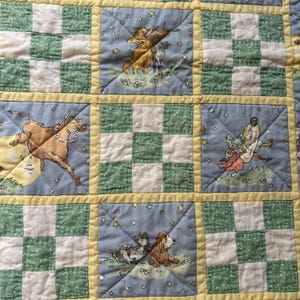 May include: A patchwork quilt featuring alternating squares of green and white checkered fabric and light blue squares with illustrations of animals, including a cow jumping over a moon, a dog playing a fiddle, and a cat, all bordered by yellow.