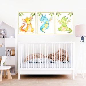 May include: Three watercolor illustrations of dragons in a nursery setting. The dragons are yellow, blue, and green. The illustrations are framed and hung on a white wall.