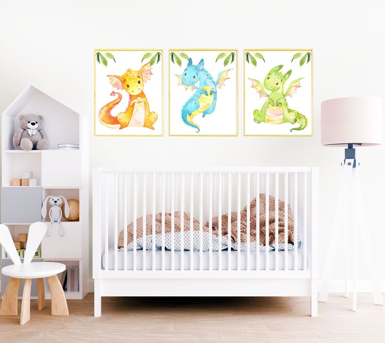 May include: Three watercolor illustrations of dragons in a nursery setting. The dragons are yellow, blue, and green. The illustrations are framed and hung on a white wall.