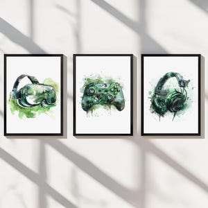 May include: Three framed watercolour illustrations of gaming accessories. The first illustration shows a green virtual reality headset. The second illustration shows a green video game controller. The third illustration shows a green pair of headphones.