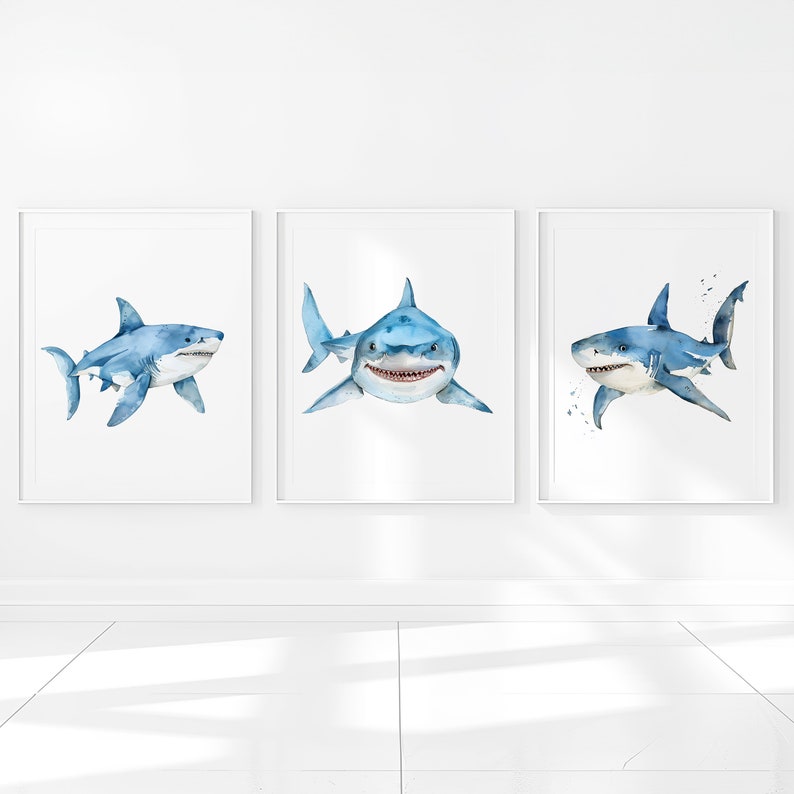 May include: Three watercolor paintings of blue sharks on a white background. The sharks are in different poses, one is facing the viewer, one is swimming to the left, and one is swimming to the right.