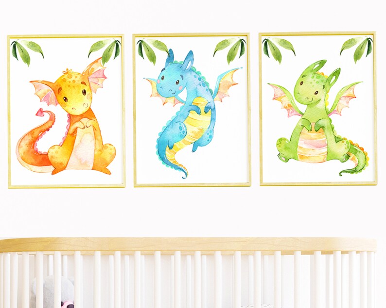 May include: Three framed watercolor paintings of cartoon dragons. The dragons are orange, blue, and green. Each dragon has a different expression and pose.