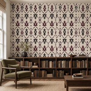 May include: Wallpaper featuring a repeating damask-style pattern in dark burgundy and charcoal gray on a cream background, applied to a wall behind a wooden bookshelf filled with books, a green armchair, and a wooden coffee table.
