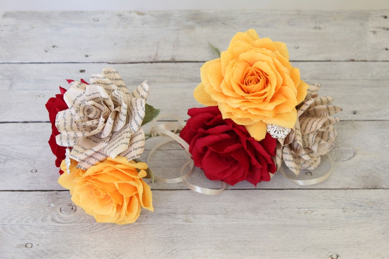 Puede incluir: Un ramo de rosas de papel en tonos rojos, amarillos y crema. Las rosas est&aacute;n hechas de p&aacute;ginas de libros y tela.