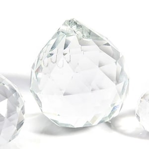 Op de afbeelding: Drie heldere kristallen prisma's in verschillende maten. De prisma's zijn gefacetteerd en hebben een traanvorm.