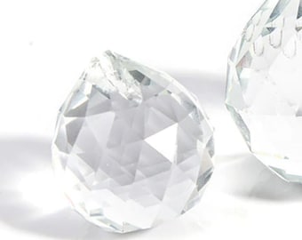 Puede incluir: Tres prismas de cristal transparentes de diferentes tamaños, con superficies facetadas que reflejan la luz.