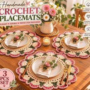 May include: Three round handmade crochet placemats featuring a scalloped edge in cream, pink, and dark green. Each placemat holds a white ceramic plate, a folded linen napkin topped with a small pink flower, and gold-toned cutlery on a wooden table.