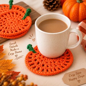 Könnte beinhalten: Ein runder, orangefarbener Häkeluntersetzer in Kürbisform mit grünem Stiel, auf dem eine weiß gesprenkelte Keramiktasse mit Kaffee steht. Der Text lautet Small Details Make a Cozy Home und Cozy Sips Happy Days mit Herzsymbolen.
