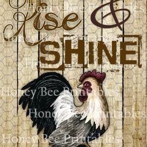 May include: A rooster with black, white, and gray feathers stands on a wooden background with a chicken wire pattern. The text "Rise & Shine" is written in brown letters above the rooster.