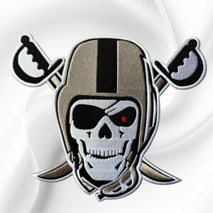 May include: An embroidered patch featuring a white skull wearing a tan and black football helmet with a black eye patch over the left eye and a single red dot on the right eye socket, positioned in front of two crossed silver and black swords.