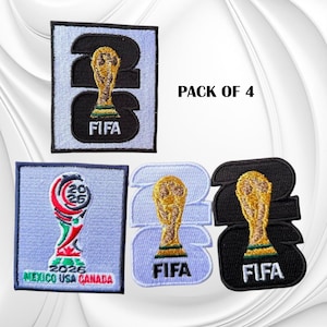 May include: A pack of 4 embroidered patches featuring the FIFA 2026 World Cup branding. The designs include the trophy icon, the number 2026, and the text Mexico USA Canada. The patches are rendered in black, white, gold, red, and green thread colors.