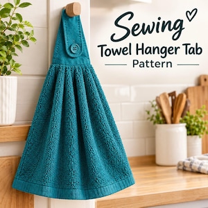 Peut inclure: Une serviette de cuisine suspendue bleu sarcelle avec un tissu texturé et absorbant, dotée d'une patte en tissu assortie fixée par un bouton. Le texte Sewing Towel Hanger Tab Pattern est écrit en bleu foncé en lettres cursives et bâton.