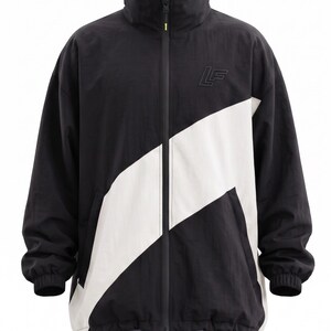 May include: A black windbreaker jacket featuring a prominent white diagonal stripe across the front. The jacket has a high collar, a full-length central zipper, and an embossed LF logo on the upper left chest. The hem and cuffs are elasticized.