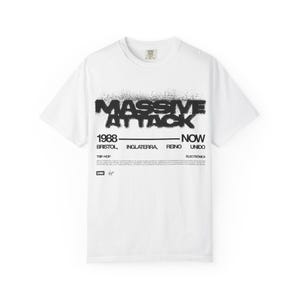 Puede incluir: Una camiseta blanca de manga corta con un estampado gráfico negro. El texto dice MASSIVE ATTACK, 1988-NOW, BRISTOL, INGLATERRA, REINO UNIDO, TRIP-HOP, ELECTRÓNICA, e incluye los logotipos de EMI y Virgin con un párrafo de texto pequeño debajo.