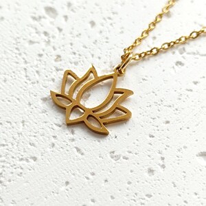 May include: A gold-toned necklace with a delicate lotus flower pendant. The pendant is a simple outline of a lotus flower.