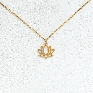May include: A gold-toned necklace with a delicate lotus flower pendant. The necklace is made of a thin chain and the pendant is a simple outline of a lotus flower.