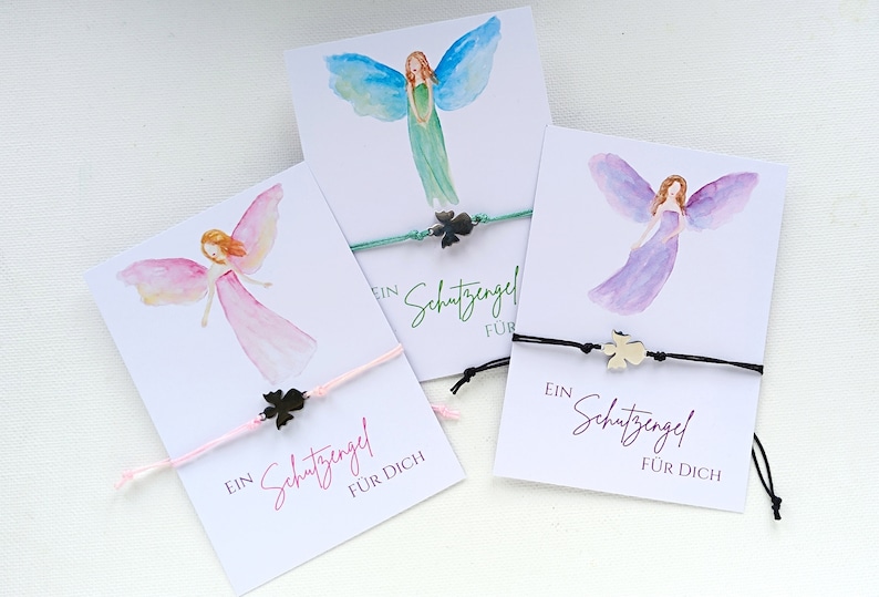 Peut inclure: Trois cartes avec des illustrations d'anges &agrave; l'aquarelle et des bracelets assortis. Chaque carte pr&eacute;sente un ange diff&eacute;rent et un bracelet avec un charm en forme de tr&egrave;fle. Le texte "Ein Schutzengel f&uuml;r Dich" est imprim&eacute; sur chaque carte, signifiant "Un ange gardien pour vous".