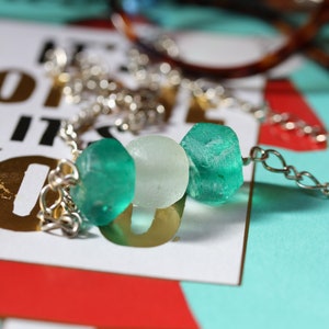 Peut inclure: Un collier en cha&icirc;ne argent avec trois perles de verre. Les perles sont vertes et blanches.
