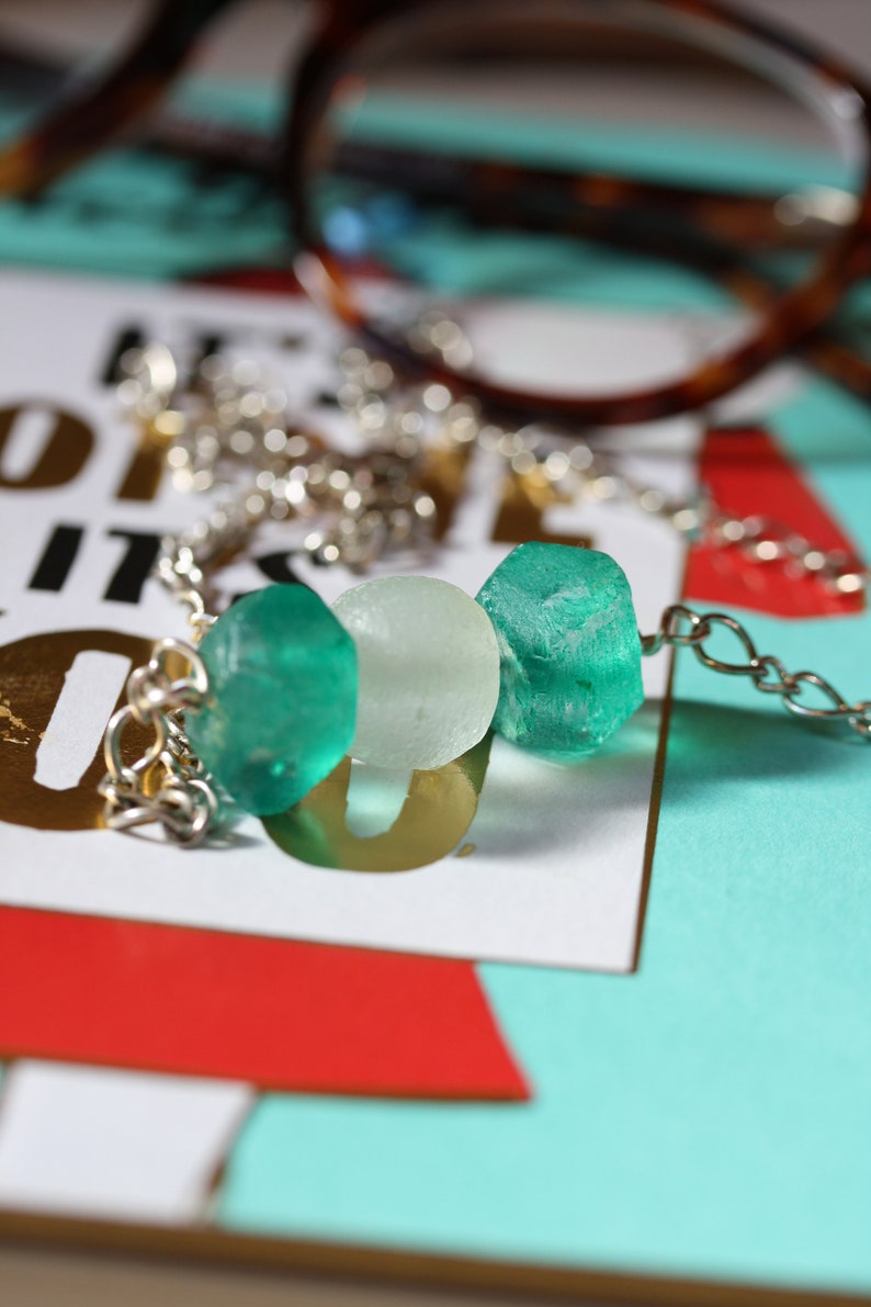 Peut inclure: Un collier en cha&icirc;ne argent avec trois perles de verre. Les perles sont vertes et blanches.