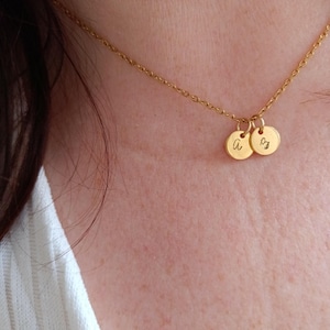 May include: A gold chain necklace with two small gold discs, one with the letter "A" and the other with the letter "S" engraved on them.