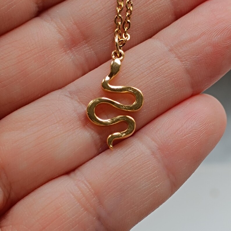 May include: A gold snake pendant necklace. The snake is curled up in a simple design.