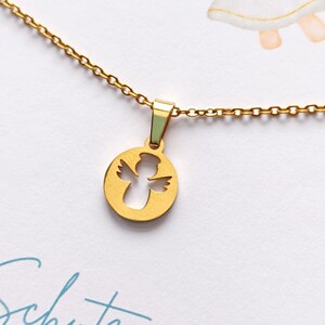 May include: A gold chain necklace with a round pendant featuring a cutout angel design. The pendant is on a white background with the text "Schutzengel f&uuml;r" in blue.