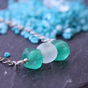 Peut inclure: Un collier en cha&icirc;ne argent avec trois perles de verre. Les perles sont vertes et blanches.