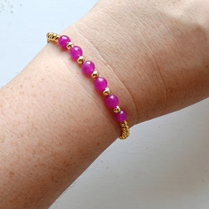 May include: A pink and gold beaded bracelet with a stretchy band.
