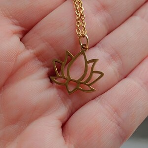 May include: A gold-toned necklace with a delicate lotus flower pendant. The chain is a simple, linked style.