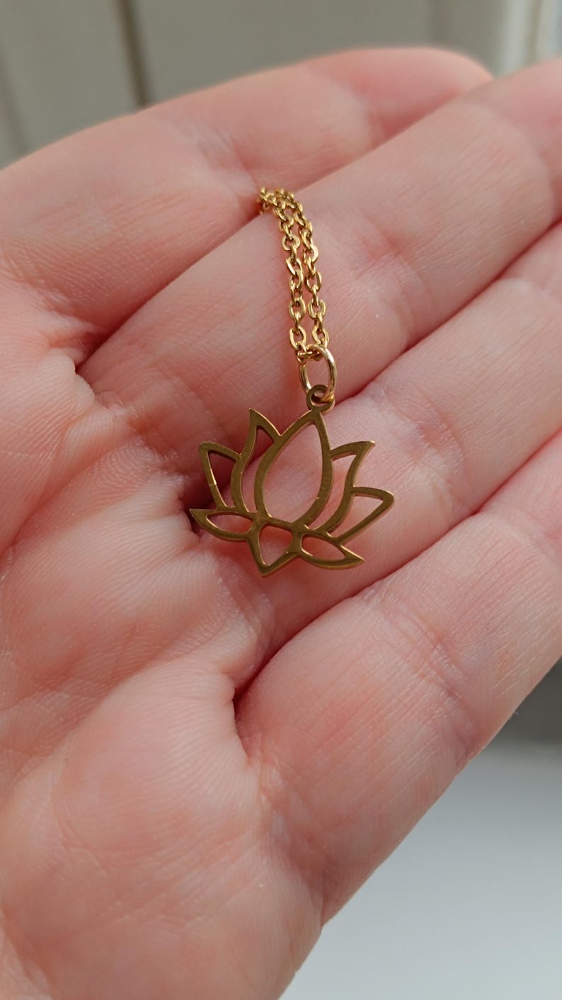 May include: A gold-toned necklace with a delicate lotus flower pendant. The chain is a simple, linked style.
