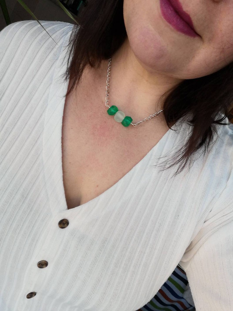 Peut inclure: Un collier en cha&icirc;ne argent avec trois perles rondes. Les perles sont vertes et blanches.