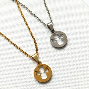 May include: Two angel pendant necklaces, one gold and one silver, with a delicate chain. The angel is cut out of the pendant, creating a silhouette.