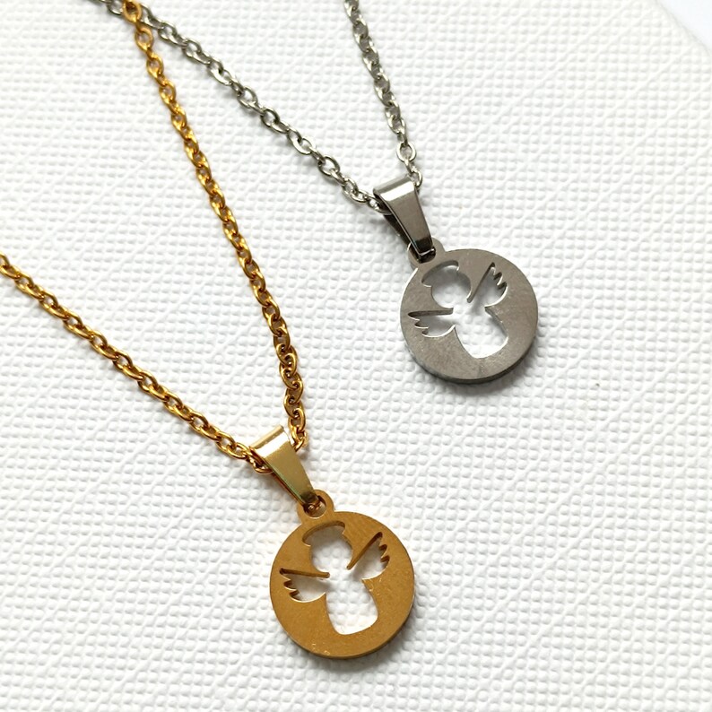 May include: Two angel pendant necklaces, one gold and one silver, with a delicate chain. The angel is cut out of the pendant, creating a silhouette.