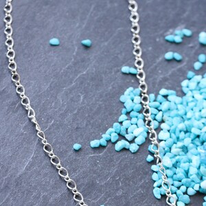 Peut inclure: Un collier en cha&icirc;ne argent avec trois perles en verre turquoise. Les perles sont un m&eacute;lange de turquoise clair et fonc&eacute;.