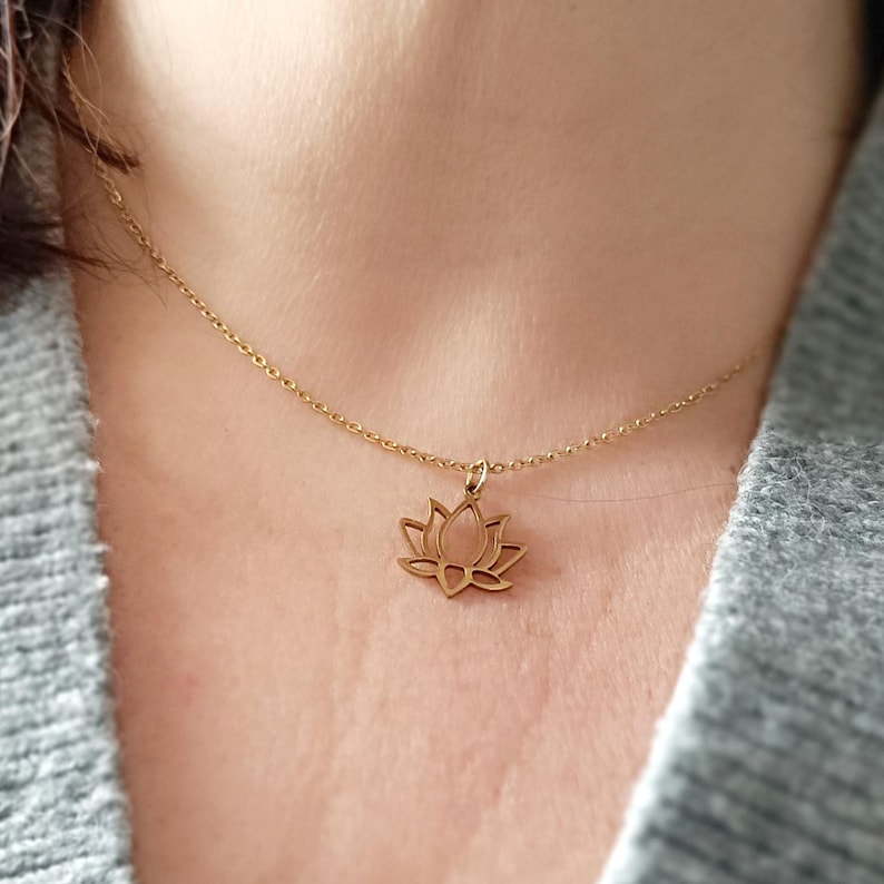 May include: A gold chain necklace with a delicate lotus flower pendant.