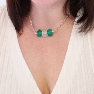 Peut inclure: Un collier en cha&icirc;ne argent avec trois perles en verre vert et blanc.
