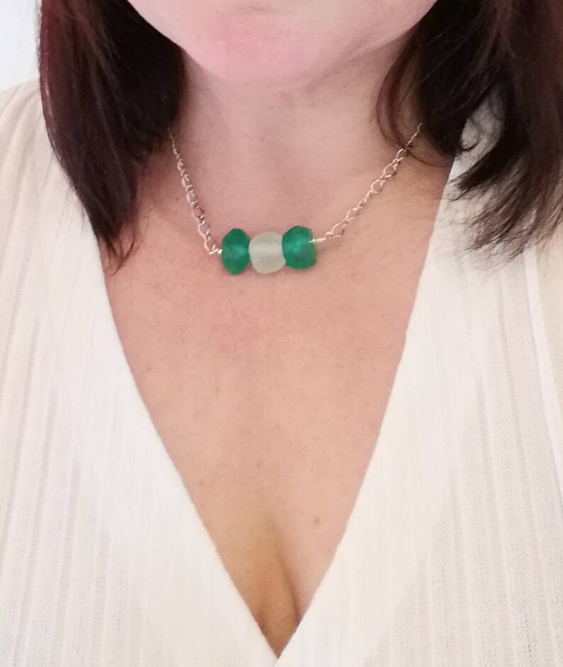 Peut inclure: Un collier en cha&icirc;ne argent avec trois perles en verre vert et blanc.
