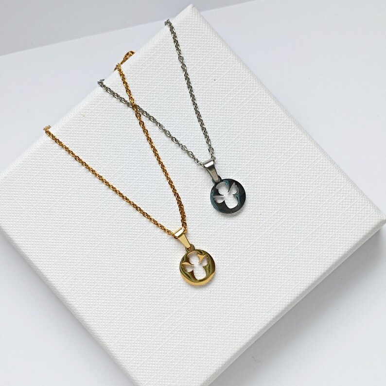 May include: Two silver necklaces with angel pendants. One necklace has a gold pendant and the other has a silver pendant.